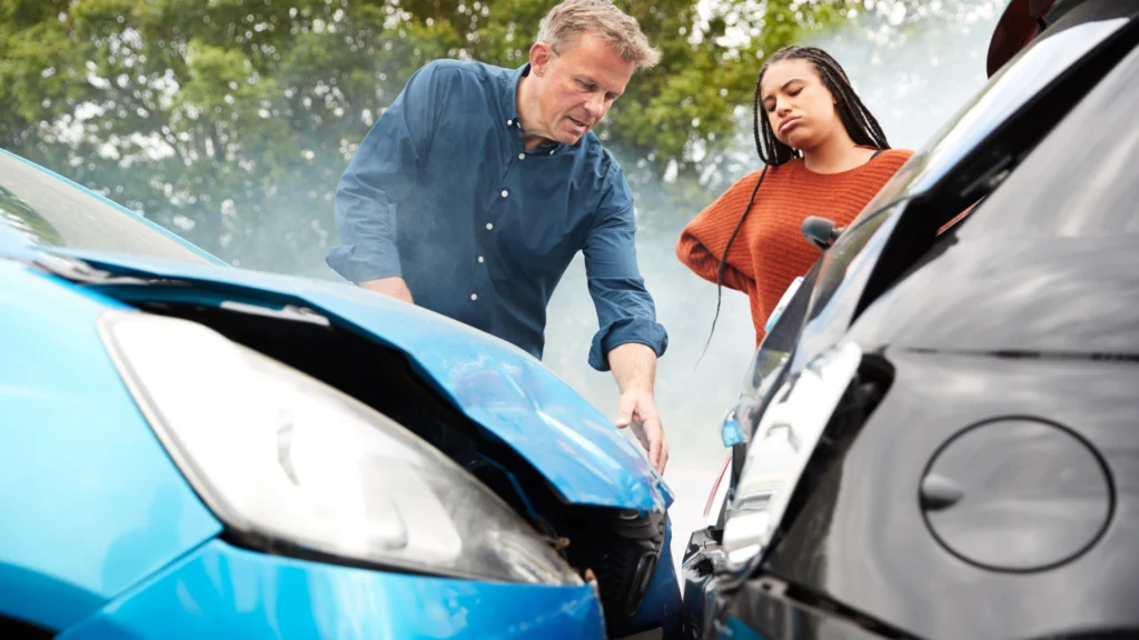 Two people inspect a car accident, raising the question: do insurance companies go after uninsured drivers for damages?