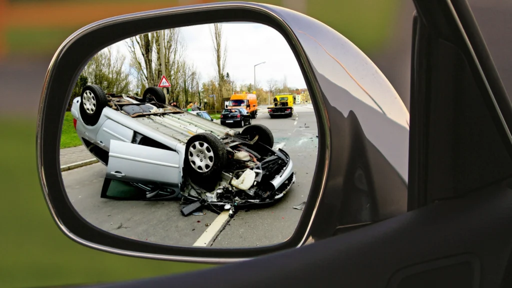 Flipped car in mirror highlights real-world need for luxury vs standard accident coverage