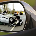 Flipped car in mirror highlights real-world need for luxury vs standard accident coverage