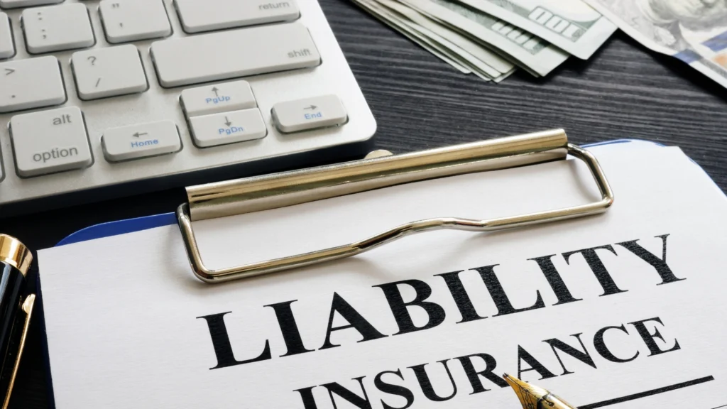 Clipboard with a liability insurance form near money and keyboard, representing property damage liability coverage