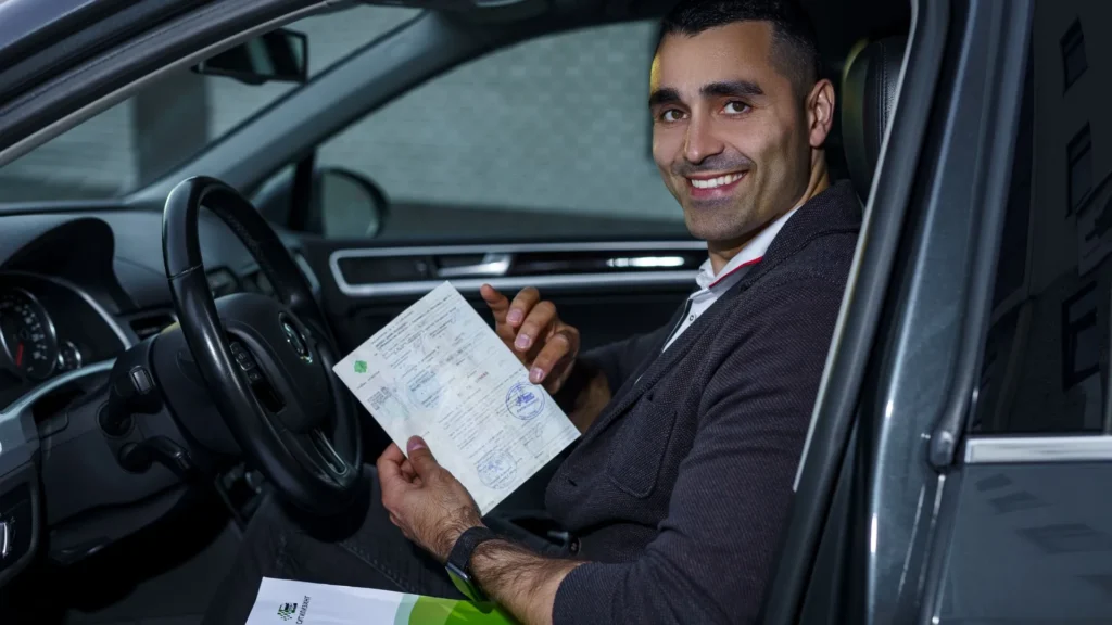 Man sitting in car holding documents after purchasing Remco auto insurance policy.