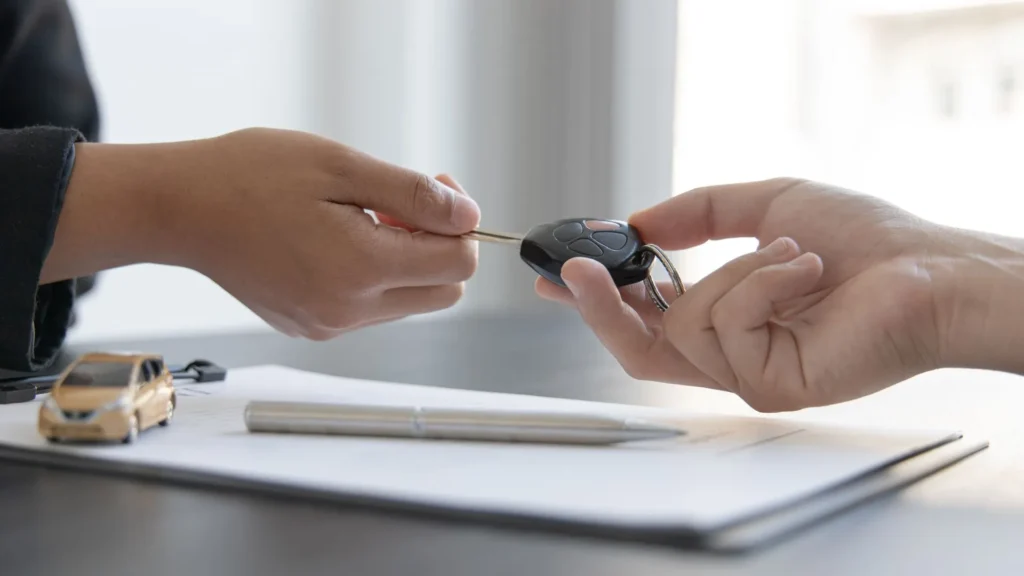 Car key handoff over paperwork symbolizing a vehicle policy with Remco auto insurance.